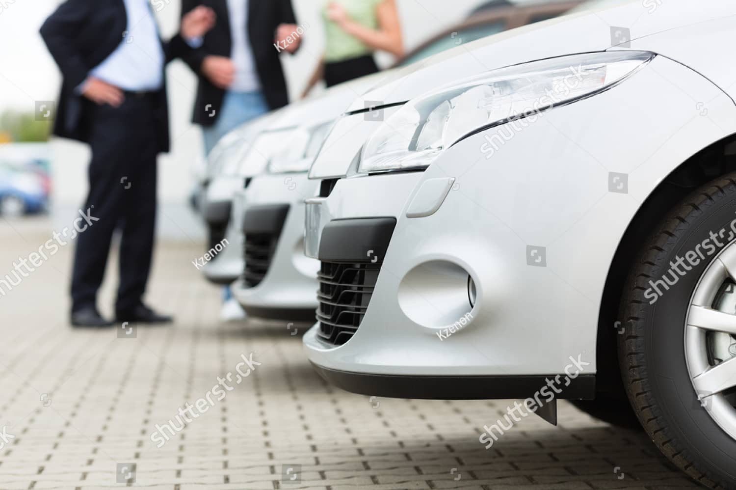 stock-photo-two-men-man-and-one-woman-stand-behind-a-row-of-silver-metallic-cars-on-a-parking-place-on-yard-of-110345132